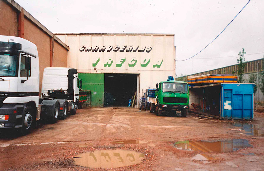 Imagen de nuestro pabellón del año 1994 con las puertas abiertas y tres camiones estacionados al lado de la puerta